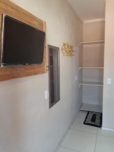 uma sala de estar com uma televisão de ecrã plano na parede em Suítes Canaã em Canoa Quebrada