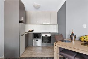 cocina con electrodomésticos de acero inoxidable y mesa de madera en Quest Yelverton Kalgoorlie, en Kalgoorlie