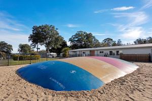 a large surfboard in the sand in front of a building at Discovery Parks - Forster in Tuncurry
