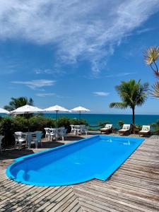 einen Pool mit Tischen und Stühlen und das Meer in der Unterkunft Pousada Jakuara in Arraial d'Ajuda