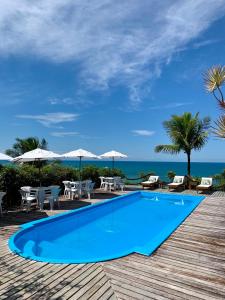 a swimming pool with tables and chairs and the ocean at Pousada Jakuara in Arraial d'Ajuda