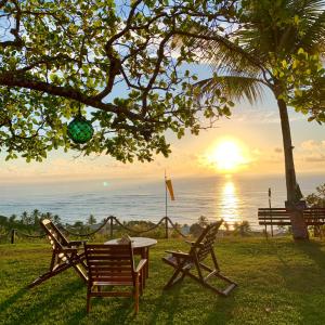 una mesa y dos sillas bajo un árbol con el océano en Pousada Jakuara, en Arraial d'Ajuda