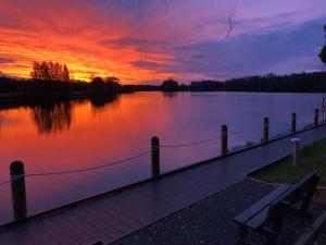 a sunset over a body of water with a bench at Discovery Parks - Forster in Tuncurry