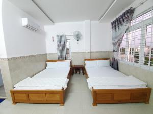 two beds in a room with two windows at Khách Sạn Thiên Phong in Buon Ma Thuot