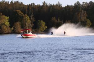 two people are water skiing on a boat on the water at Discovery Parks - Forster in Tuncurry