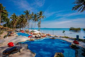a resort pool with palm trees and the ocean at Villa Cha-Cha Krabi Beachfront Resort in Ao Nam Mao
