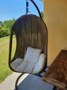 a wicker chair with a pillow sitting next to a table at Kerikeri Blue Chair B&B in Kerikeri