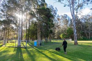 a woman walking a dog in a park at Discovery Parks - Forster in Tuncurry