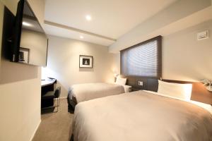 a hotel room with two beds and a desk and a window at S-peria Inn Nihombashi Hakozaki in Tokyo