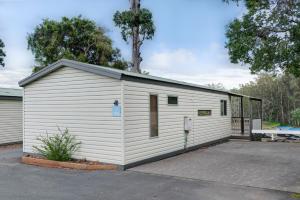a large white garage with a tree behind it at Discovery Parks - Forster in Tuncurry