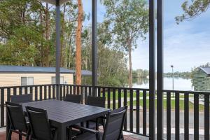 a table and chairs on a balcony with a view of a lake at Discovery Parks - Forster in Tuncurry
