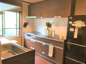 eine Küche mit einer Spüle und einem schwarzen Kühlschrank in der Unterkunft K's House Hostels - Hakone Yumoto Onsen in Hakone