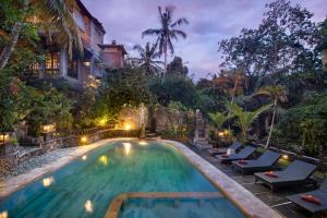 a swimming pool with lounge chairs and a house at Ketut's Place Bed & Breakfast Ubud in Ubud