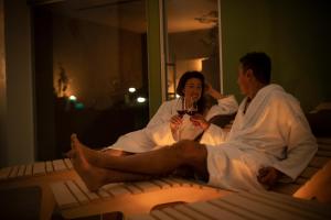 a man and woman sitting on a bed with a glass of wine at Hotel Piuro in Prosto di Piuro