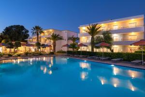 a swimming pool in front of a hotel at night at Meliton Hotel in Theologos