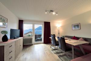 Ferienwohnungen Tiroler Alpenhof في إنسبروك: غرفة معيشة مع طاولة وكراسي وتلفزيون