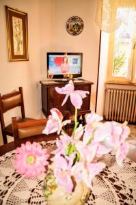 グッビオにあるAppartamento Gubbio Vacanzeのリビングルーム(ピンクの花が飾られたテーブル付)
