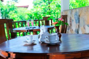 una mesa de madera con dos tazas de té y un jarrón en Residence Chanty, en Hikkaduwa