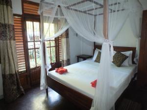 una camera da letto con un letto bianco con baldacchino di Abraham Beach House a Tangalle