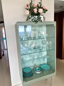 a glass cabinet with plates and a vase with flowers at Vista Bella. Apartamentos in Calpe