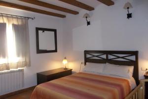 um quarto com uma cama, um espelho e uma janela em Casa Rural El Temple em Las Cuevas de Cañart