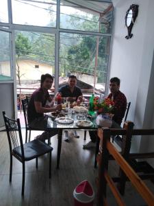 Eine Gruppe von drei Männern, die um einen Tisch sitzen. in der Unterkunft The Peak Residence in Nallathanniya