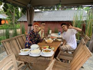 un grupo de tres personas sentadas en una mesa con comida en Batur Sunrise Guesthouse en Kintamani