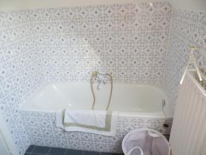 eine weiße Badewanne im Bad mit Tapete in der Unterkunft Villa Eleonore in Koksijde + 25 Fotos