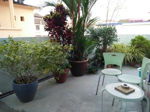a patio with a table and chairs and potted plants at Sojourn Beds & Cafe in Taiping