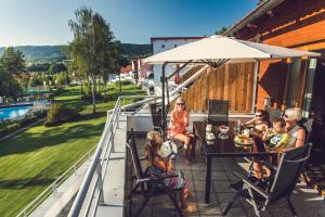 um grupo de pessoas sentadas numa mesa numa varanda em Lipno Lake Resort em Lipno nad Vltavou