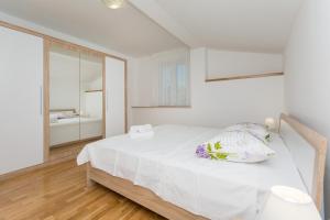 a white bedroom with a bed and a mirror at Courtyard seafront house in Kaštela