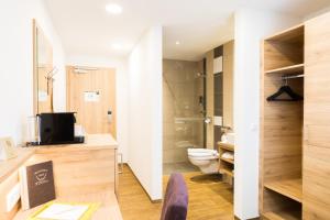 a bathroom with a toilet and a television in it at Hotel Stiegler Bed & Breakfast in Timelkam