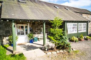 ein Cottage aus Stein mit einer weißen Tür und einigen Pflanzen in der Unterkunft Comrie Croft in Crieff