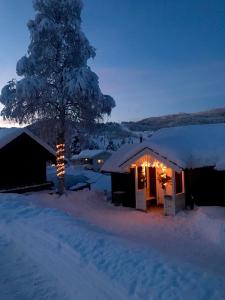 a snow covered cabin with a tree in the snow at Tuddal Hyttegrend, GAMLESTUGU, Telemark in Tuddal