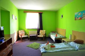 Habitación con paredes verdes y dormitorio con cama. en Hotel Ostaš Police nad Metují, en Police nad Metují