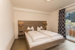 sypialnia z dużym łóżkiem i dużym oknem w obiekcie Haus Garni Luggi Leitner w mieście Mittelberg