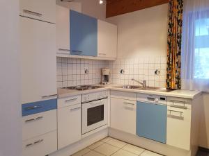 a kitchen with white cabinets and blue appliances at Apart Foresta in Samnaun