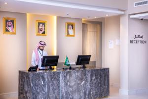 a man standing at a reception desk in a hotel lobby at Kyona Al Qurayat - كيونا القريات in Jeddah