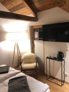 een slaapkamer met een bed en een stoel en een flatscreen-tv bij Bootshaus am Hallstätter See in Hallstatt