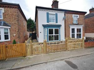 a wooden fence in front of a white house at EasyRest Spalding - 6 Beds & Free Parking - Central & Quiet Location - Entire Spacious House in Spalding