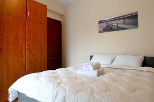 a bedroom with a white bed with a wooden cabinet at Papi's Free Parking Apartments 2 - 2 Bedroom in Alexandroupoli