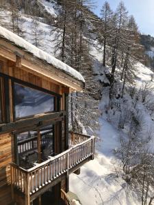 une cabane en rondins dans la neige avec un balcon dans l'établissement Chalet Carte Blanche Ubud, à Tignes