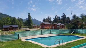 a swimming pool with a fence and a house at Complejo Loncopangue Lodge in Loncopangue