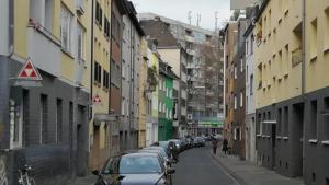 una calle de la ciudad con coches aparcados en la calle en Fewo CityLife Köln-Innenstadt en Colonia