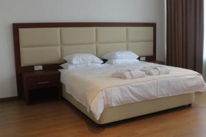 a bedroom with a large bed with white sheets and pillows at Union Hotel Grozny in Groznyy
