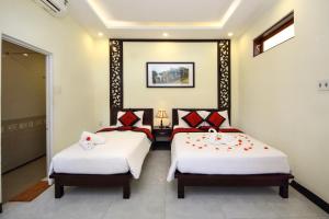 duas camas num quarto com branco e vermelho em Fireworks Homestay em Hoi An