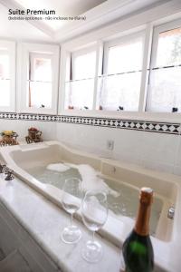a bath tub with two wine glasses and a bottle at Villa da Esperança in Campos do Jordão