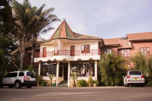 een gebouw waar auto's voor geparkeerd staan bij The Charity Hotel International in Arusha