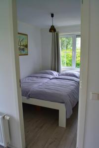 Cama en habitación con ventana en Vakantiewoning aan duinen en zee in Dishoek, en Dishoek