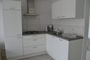 una cocina blanca con armarios blancos y fregadero en Vakantiewoning aan duinen en zee in Dishoek, en Dishoek